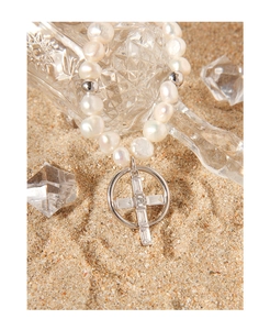 Vue macro d'un collier de perles naturelles avec pendentif croix en zircon sur le sable