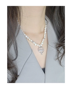 Détail d'un pendentif croix en argent S925 avec zircon sur collier de perles