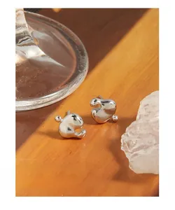 Macro shot of S925 sterling silver liquid heart earrings on aesthetic wood background