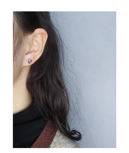 Close-up of minimalist S925 sterling silver heart studs worn on a female ear