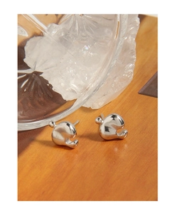 Macro shot of silver liquid geometric earrings with polished finish on brown texture