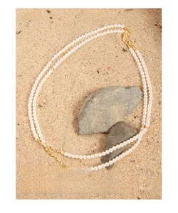 Detail of double-layer pearl necklace with gold clasp on a natural stone background