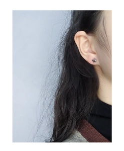 Close-up of minimalist black spade heart stud earrings worn by a model in a trendy style