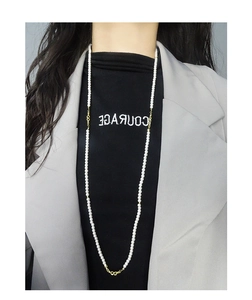Long white pearl necklace with gold infinity charms worn as a layered sweater chain