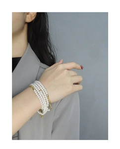 Detail of elegant four-layer pearl bracelet with gold bead accents on a woman wrist