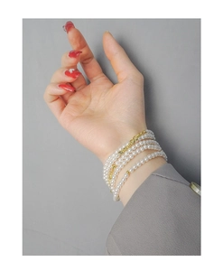 Detail of multi-layer white pearl bracelet with gold lobster clasp on female wrist