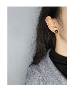 Close-up of S925 silver four-leaf clover stud earring with black enamel on model ear