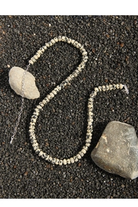 Detailed macro view of natural Dalmatian Jasper beaded necklace on dark textured stone