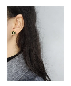 Close-up of S925 silver four-leaf clover stud earring with black enamel on a model
