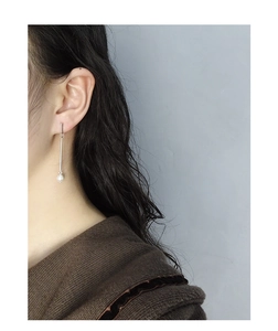 Close-up of minimalist S925 silver long drop earring with round white pearl on model
