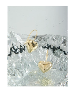 Detailed view of gold S925 heart earrings with hallmark on water ripple background