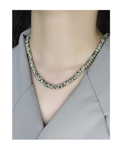 Close-up of Dalmatian Jasper beaded necklace worn over a grey blazer for a modern look