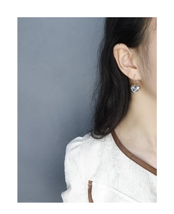 Detailed view of silver heart earrings with a high-polish finish on a female model
