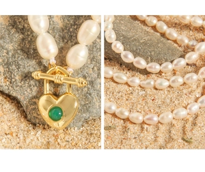 Macro detail of heart-shaped gold locket with green gem and white freshwater pearls