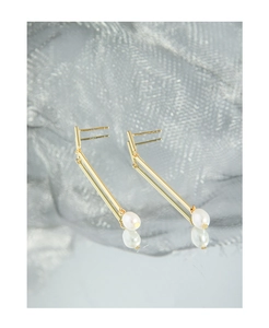 Detail of s925 silver needle stamp on golden bar earrings with elegant oval pearls