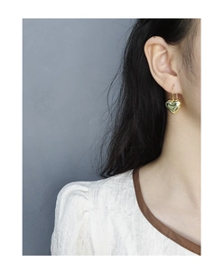 Close-up of woman wearing high-polished gold heart drop earrings in a minimalist style
