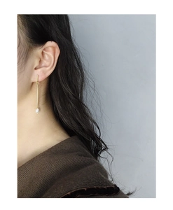 Minimalist long gold bar drop earrings with elegant white pearl on female model