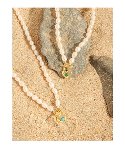 Detail of S925 silver pearl necklace with heart pendant and green blue stone inlay
