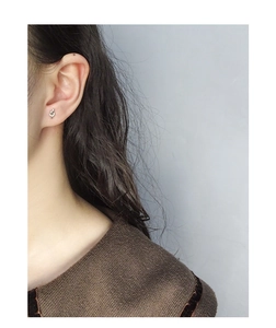 Close-up of S925 sterling silver treble clef note stud earrings worn by a model