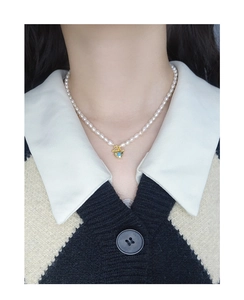 Detail of S925 silver pearl necklace with golden heart pendant and blue stone