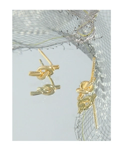 Macro detail of gold-plated geometric knot earrings with polished minimalist finish