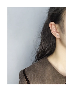 Close-up of minimalist S925 sterling silver music note stud earrings worn by a model