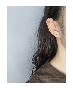Close-up of minimalist gold knot stud earring worn by a model for a chic daily look