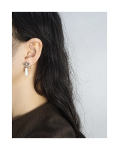 Close-up of S925 silver bow earrings with a white teardrop pearl on a female model