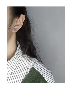 Macro shot of silver Fu character earrings on model showing delicate S925 sterling texture