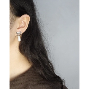 Elegant S925 silver bow earrings with white water drop pearl charms worn by a model