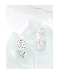 Macro shot of S925 silver asymmetric stud earrings with Fu character and white moonstone