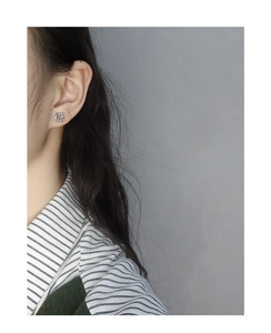 Close-up of minimalist S925 silver stud earring featuring the Fu character on a model