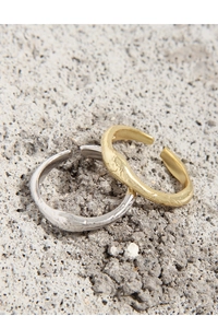 Close-up of matte fluid irregular S925 silver rings on a rustic stone background