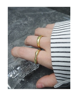 Detail of matte gold irregular hammered stackable rings worn on a woman's hand
