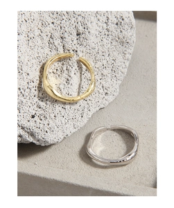 Macro detail of silver and gold irregular lava textured open rings on volcanic stone