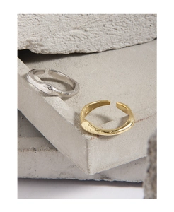 Detail of adjustable matte lava texture rings in gold and silver on stone