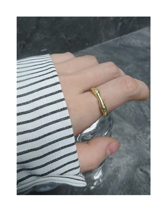 Detailed close-up of a matte gold irregular molten lava texture ring on finger