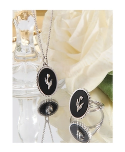 Detailed close-up of S925 silver tulip black agate necklace and ring set on white petals