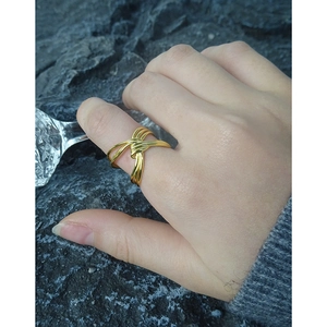 Anello a nodo in argento S925 dorato sulla mano su sfondo di roccia grigia scura