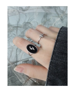 Detail of tulip engraved black agate ring and silver floral band worn on hand