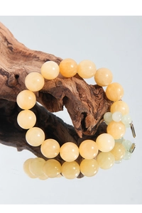 Detail of yellow topaz bracelet with pink agate beads displayed on elegant wood