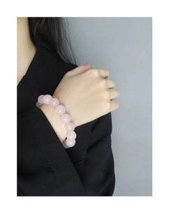Detailed close-up of rose quartz beaded bracelet worn by a model in a minimalist setting