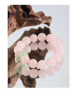 Macro detail of natural pink quartz beads and silver clasp on a zen wood display