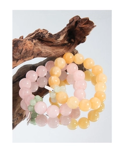Detailed close-up of beaded bracelets with pink agate and natural yellow topaz on wood