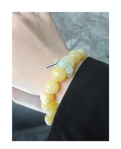 Detail of natural yellow topaz beaded bracelet with silver charm on model's wrist