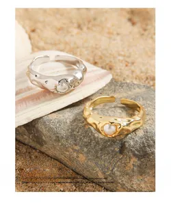 Unregelmäßige gehämmerte offene Ringe mit weißen Perlen auf Strandmuscheln und Sand
