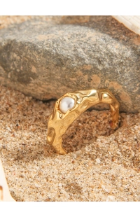 Nahaufnahme eines S925 Silberrings mit Goldtextur und weißer Perle auf echtem Strandsand