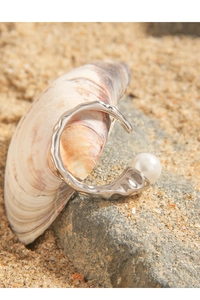 Close-up of S925 silver ring with pearl on beach sand and sea shell decorations