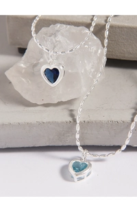 Detail showing two heart-shaped blue zircon pendants on elegant silver chain necklaces