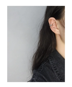 Detail of silver chain ear cuff clip on female model wearing black denim jacket
